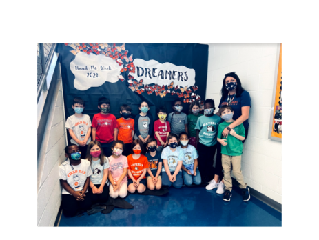 1st grade Teacher Codi Cummings and a group of students in masks in front of a wall that says "Dreamers" and "Read Me Week 2021."