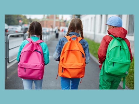Three children with bright backpacks walking to school