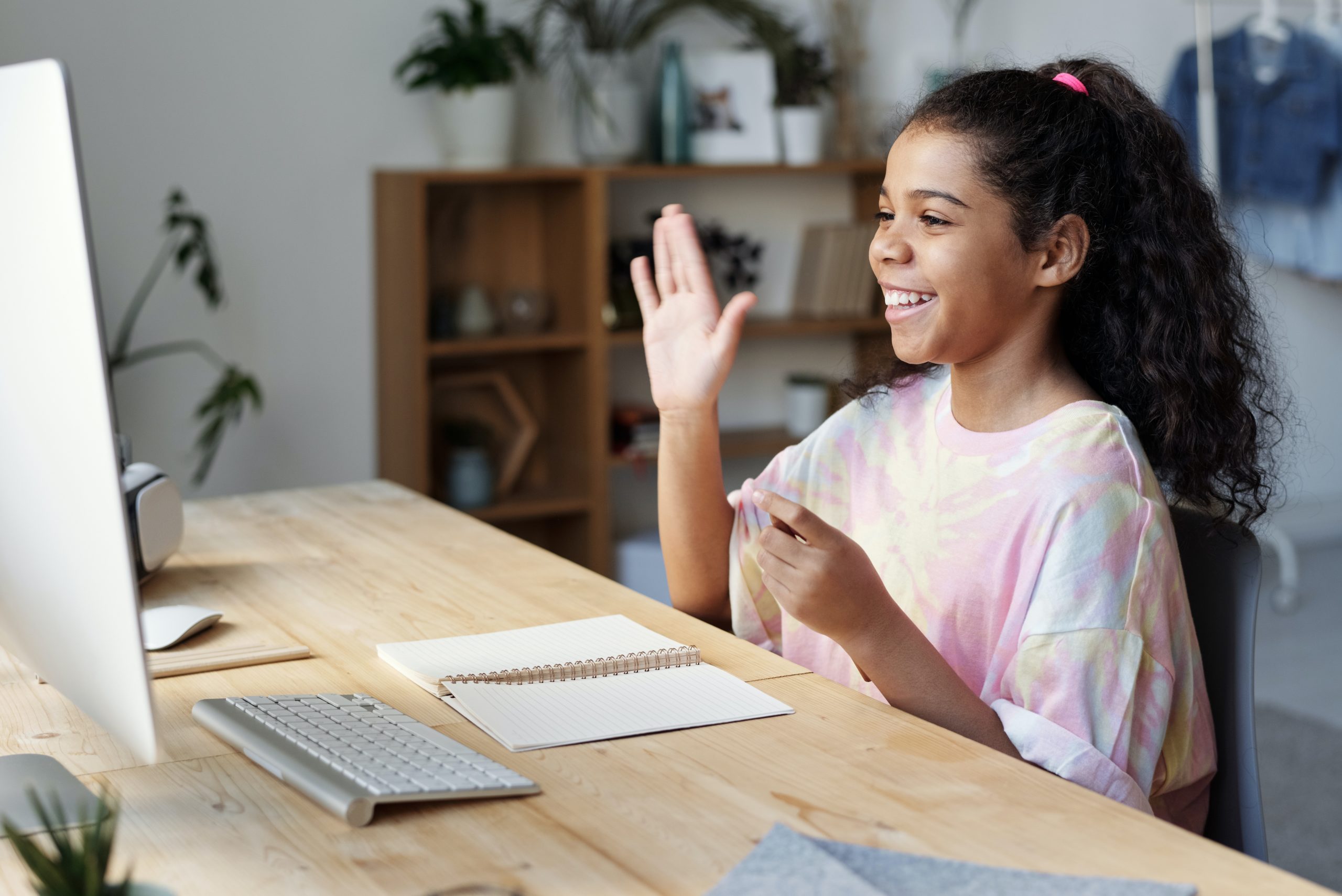 a child waving at her classmates on the computer