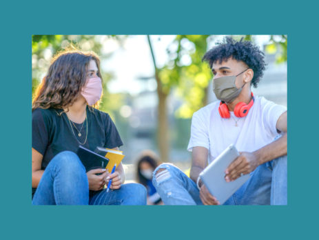 Students with masks on having a conversation.